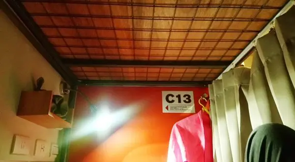 床的一邊有插座、檯燈、門禁卡放置處跟木頭置物架,以及雙頭吊衣鉤